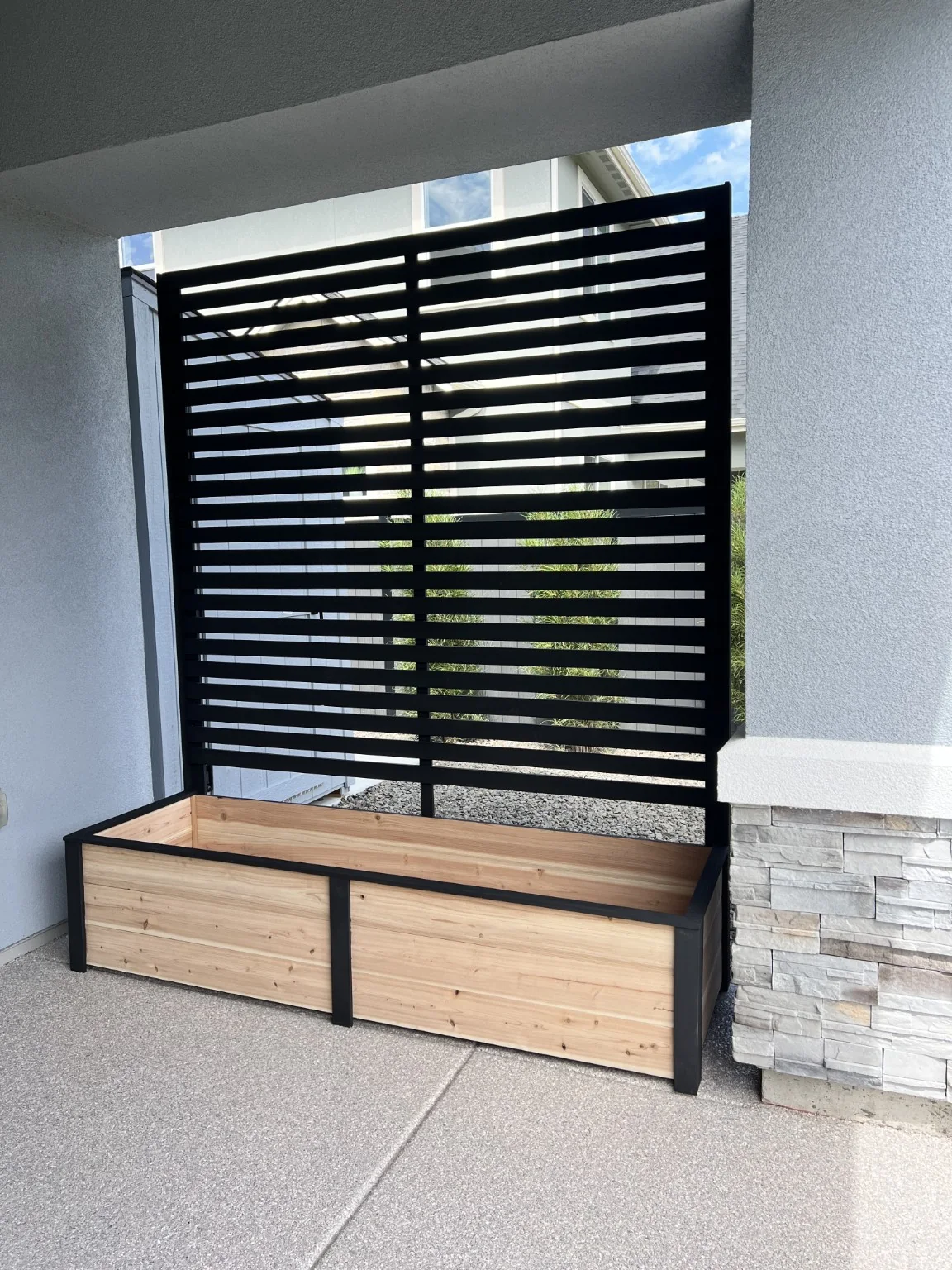 Angled view of a custom cedar privacy planter installed on a covered patio